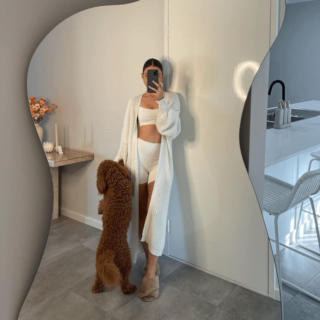 Curvy irregular mirror reflecting modern interior with stylish decor and natural light, perfect for enhancing bedrooms or living spaces in UAE homes.