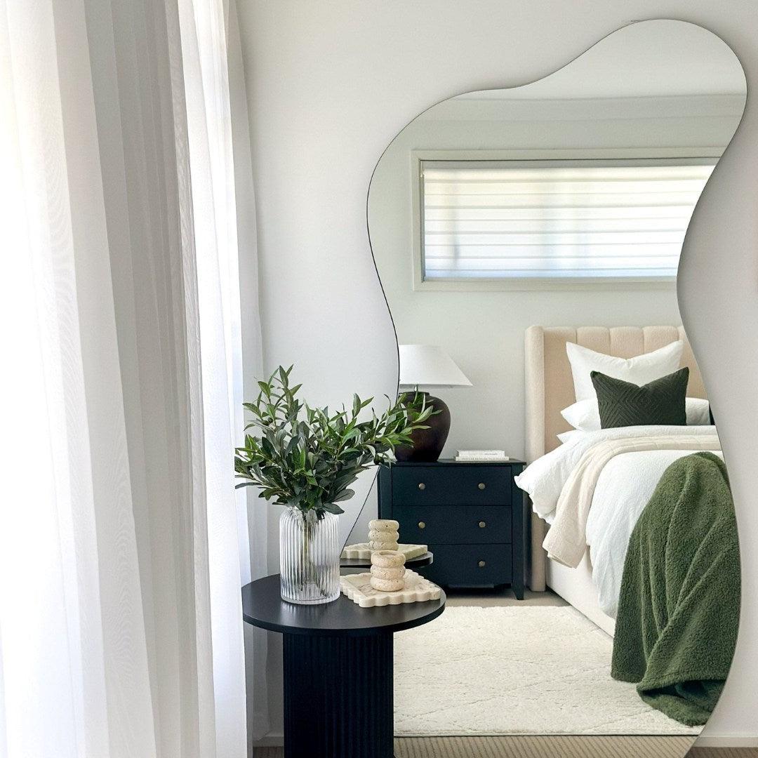 Curvy irregular mirror reflecting a stylish bedroom with minimal decor, perfect for modern UAE interiors. Full-length mirror with artistic design.
