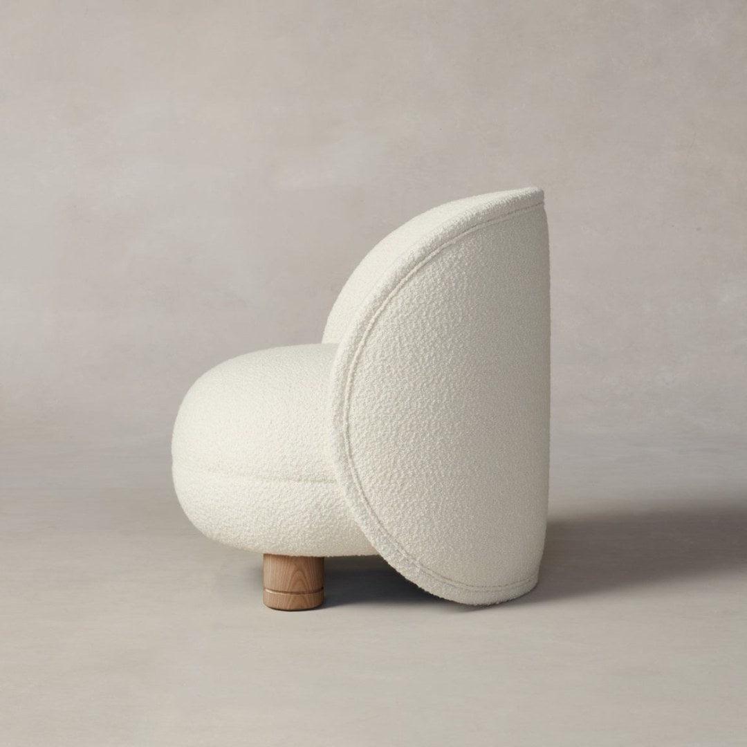 Side profile of the Dima Boucle Armchair with boucle fabric upholstery and wooden legs, featuring a sleek, modern design for elegant interiors.