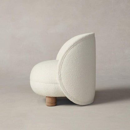 Side profile of the Dima Boucle Armchair with boucle fabric upholstery and wooden legs, featuring a sleek, modern design for elegant interiors.