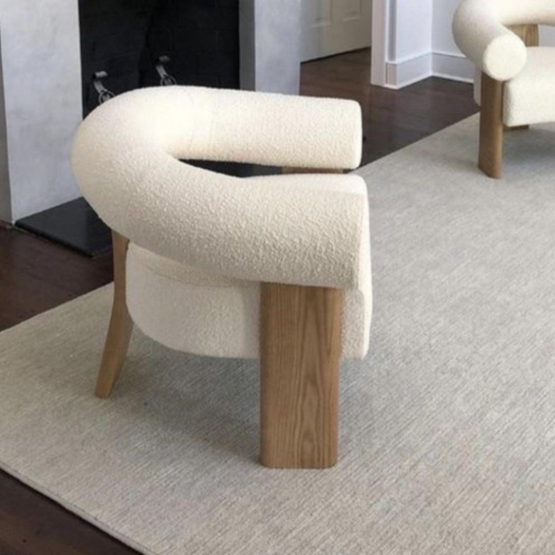 Side view of the Polly Wooden Leg Armchair with boucle fabric upholstery and long wooden legs, perfect for modern and elegant living spaces.