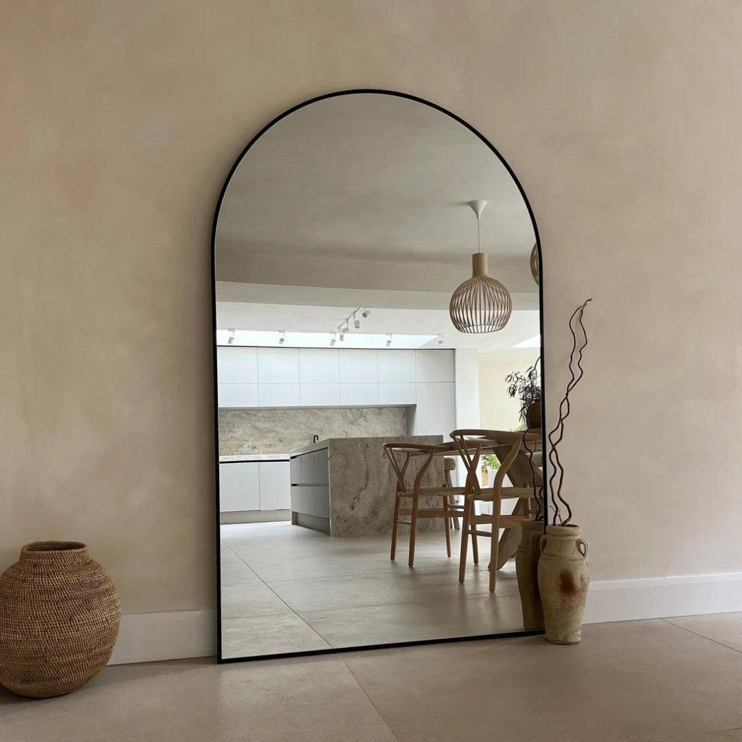 Modern Kylie arch mirror with black aluminum frame reflecting a stylish dining area, ideal for enhancing large spaces and adding elegance to UAE interiors.